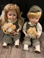 Front view of both dolls seated with their plush toys