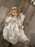 Full view of porcelain angel doll in white gown with wings and tiara
