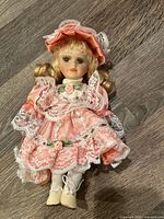 Full view of Victorian-style porcelain doll on wooden surface