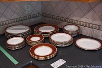 Full view of stacked Aynsley bone china plates and bowls, two coordinating patterns visible, including dinner, sandwich, and side plates with matching bowls.