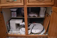 Kitchen cabinet with Foreman grill, Oster stand mixer, manual kitchen scale, and blender base missing.