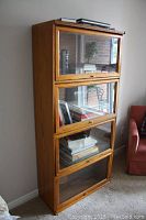 Front view of oak finish four-tier barrister style bookcase loaded with books