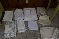 Top-down view of assorted folded white and cream linens on carpeted floor