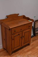 Side-angle photo of pine wood cabinet showing drawer and double door storage.
