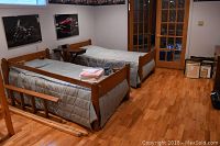 Two disassembled twin bed frames in room with bedding and ladder laid out on floor
