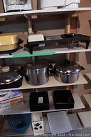 Photo of shelves showing pots, pans, roasting pan, vacuum bags and wrap, and plastic storage containers