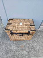 angled view of closed wicker trunk showing lid, locking bar, overall wear