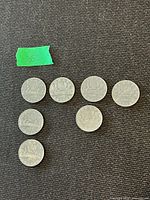 Seven Canadian Voyageur dollar coins laid out on dark fabric