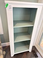 Front view of white wood display cabinet with three light aqua shelves