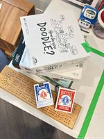 Stacked games, playing cards and cribbage board visible