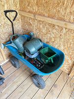 Overall lot showing blue cart, two watering cans, spreader, tin with nozzles