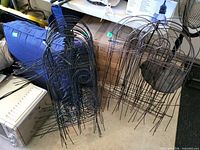Stacks of black and brown metal garden fence panels leaning against wall