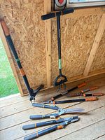 Group of Fiskars long-handled tools and cutting tools on shed floor
