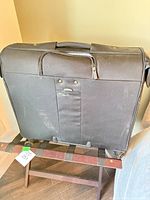 Rear view of black rolling garment bag on folding bench