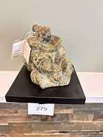 Front view of soapstone carving on pedestal with tag visible