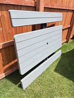 Grey resin tabletop and benches leaning against fence