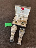 Group shot of cufflinks, tie clip, lapel pin in case, Sharp watch, Seiko watch