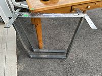 Pair of chrome table legs leaning against surface, showing full rectangular shape