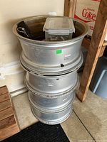 Stack of four silver rims with container of lugs and hitch inside top rim