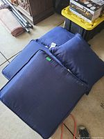 Stack of three navy blue seat cushions showing overall condition and color