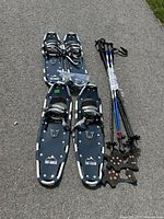 Two pairs of snowshoes, three pole pairs bundled, ice cleats and extra tips on pavement