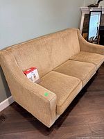 Full view of beige fabric sofa with care kit resting on seat