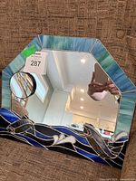 Front view of stained glass mirror showing fish design and dimensions tag