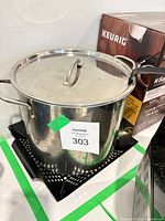 Stainless steel stock pot with lid resting on black perforated basket