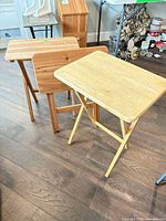 Two wooden folding tray tables shown standing, illustrating surface condition and wood tones