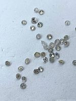 Loose round diamonds scattered on white background showing size and cut