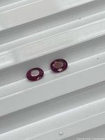 Two oval cut rubies on white background showing color and shape