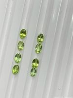 Eight lime-green oval peridots displayed in two columns