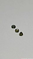 Three faceted green-yellow sapphires on neutral background
