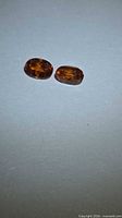 Two oval orange garnets on neutral background