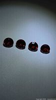 Four round deep red garnets aligned on light background