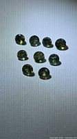 Nine small faceted green sapphires arranged on a light background