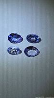 Four oval faceted Tanzanite gemstones displayed under light