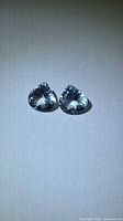 Pair of heart-cut light blue gemstones on neutral background