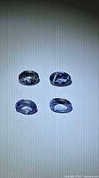Four oval tanzanite gemstones on neutral background