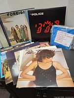 Stack of LPs showing Foreigner, The Police Ghost in the Machine and Pat Benatar front covers plus Ampex reel and others