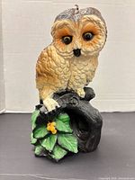 Front view of owl candle on branch with foliage