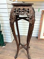 Full view of carved hardwood jardinière stand showing legs, apron, and stretcher