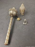 Prayer wheel, Buddha head, and small seated Buddha grouped on dark surface