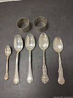Five sterling spoons and two napkin rings laid out