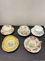 Group of five cup and saucer sets on black surface