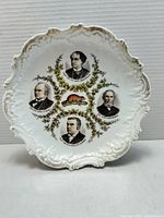 Front view of decorative plate showing portraits, beaver motif and scalloped gilt rim