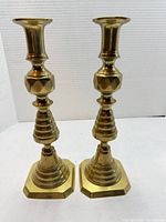 Front view of both brass candlesticks showing overall design and height