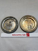 Two silver-plated presentation plates with ruler for scale