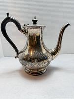 Full side view of teapot showing shape, handle, spout, engraving