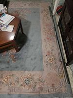 Central field and border of blue-gray and beige rug under table